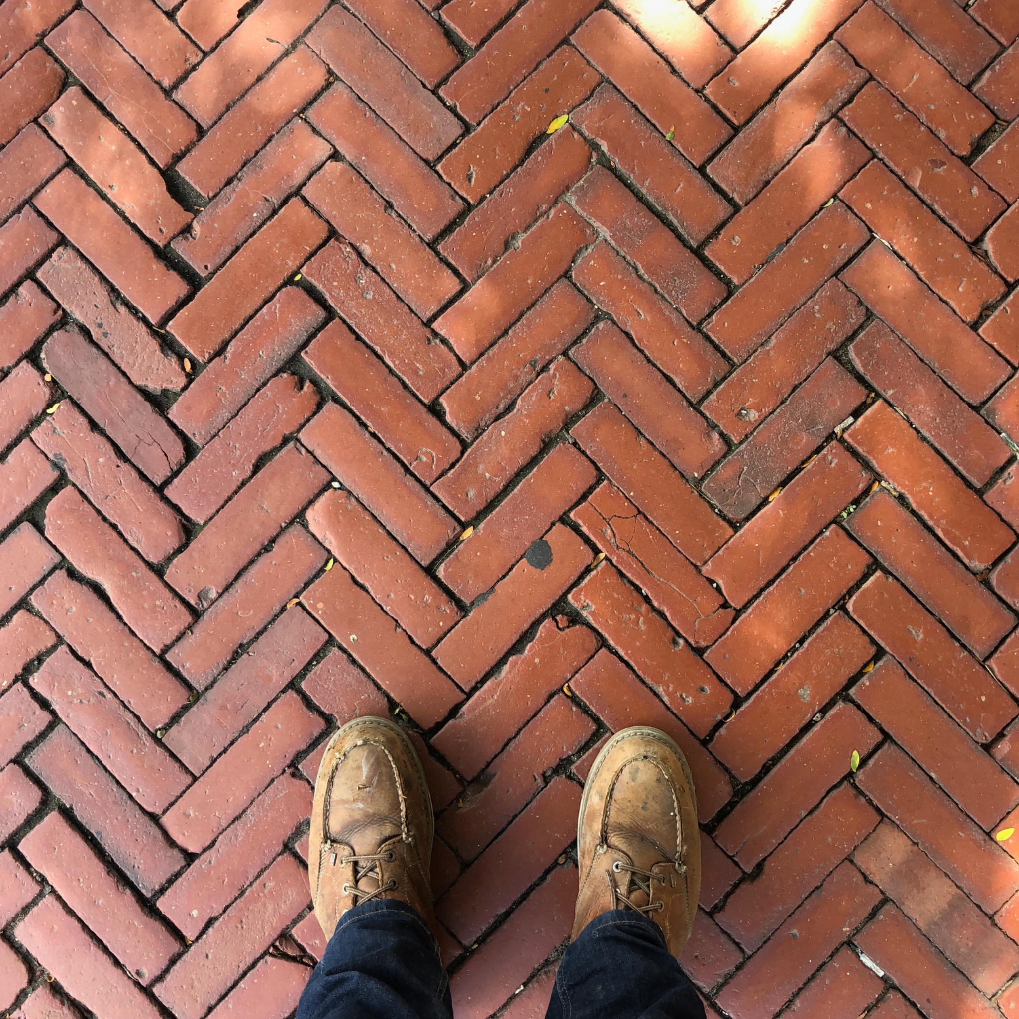 Work boots on a herringbone brick walkway